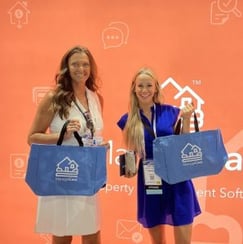 Attendees at a ManageCasa conference booth holding branded tote bags in front of the company’s event backdrop.